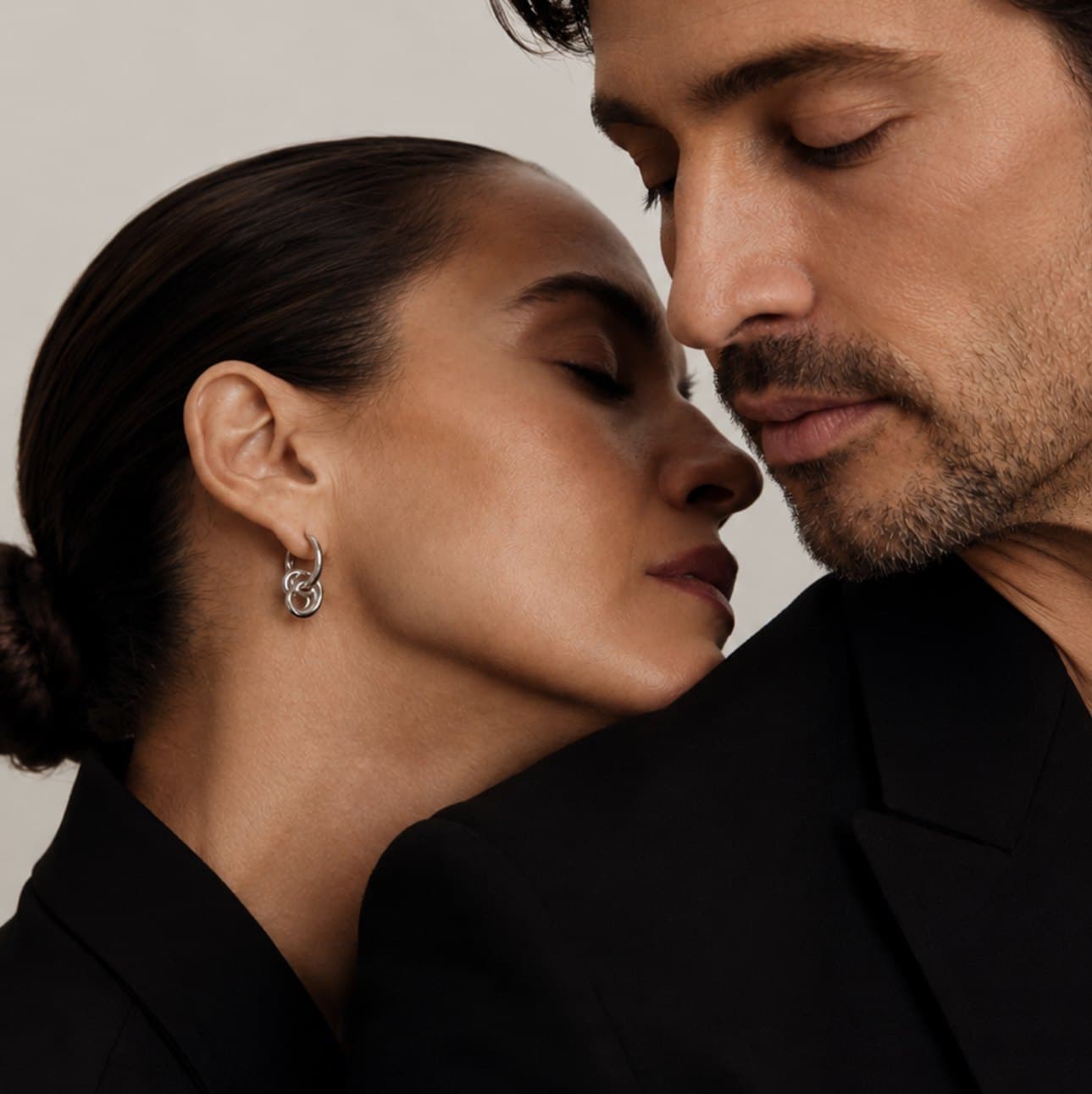 A couple in black, close together with eyes closed