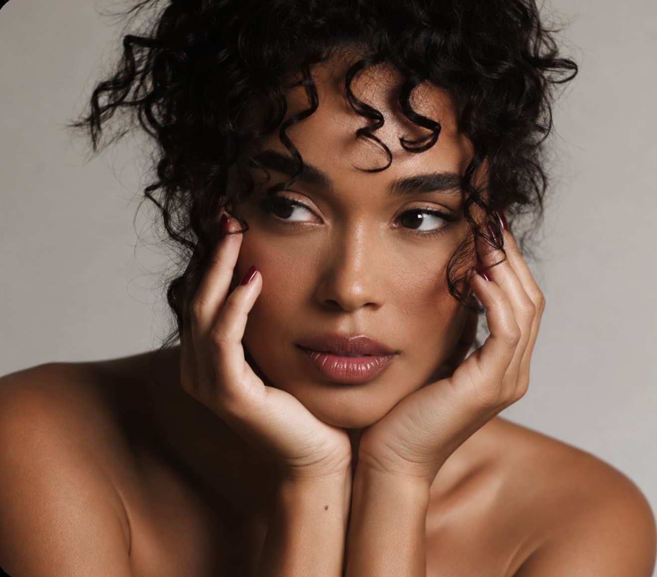 A woman with curly hair resting her face in her hands