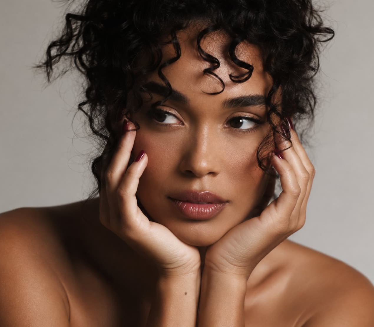 A woman with curly hair resting her face in her hands