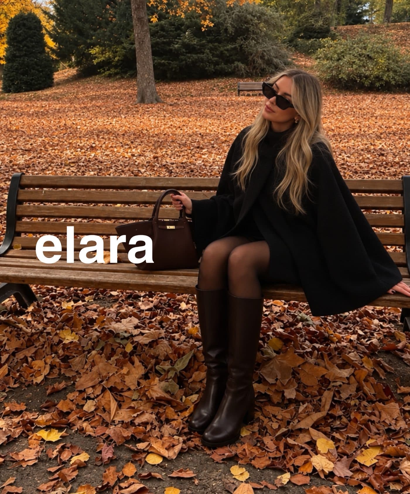 A woman in a black coat and boots sitting on a park bench among fallen leaves