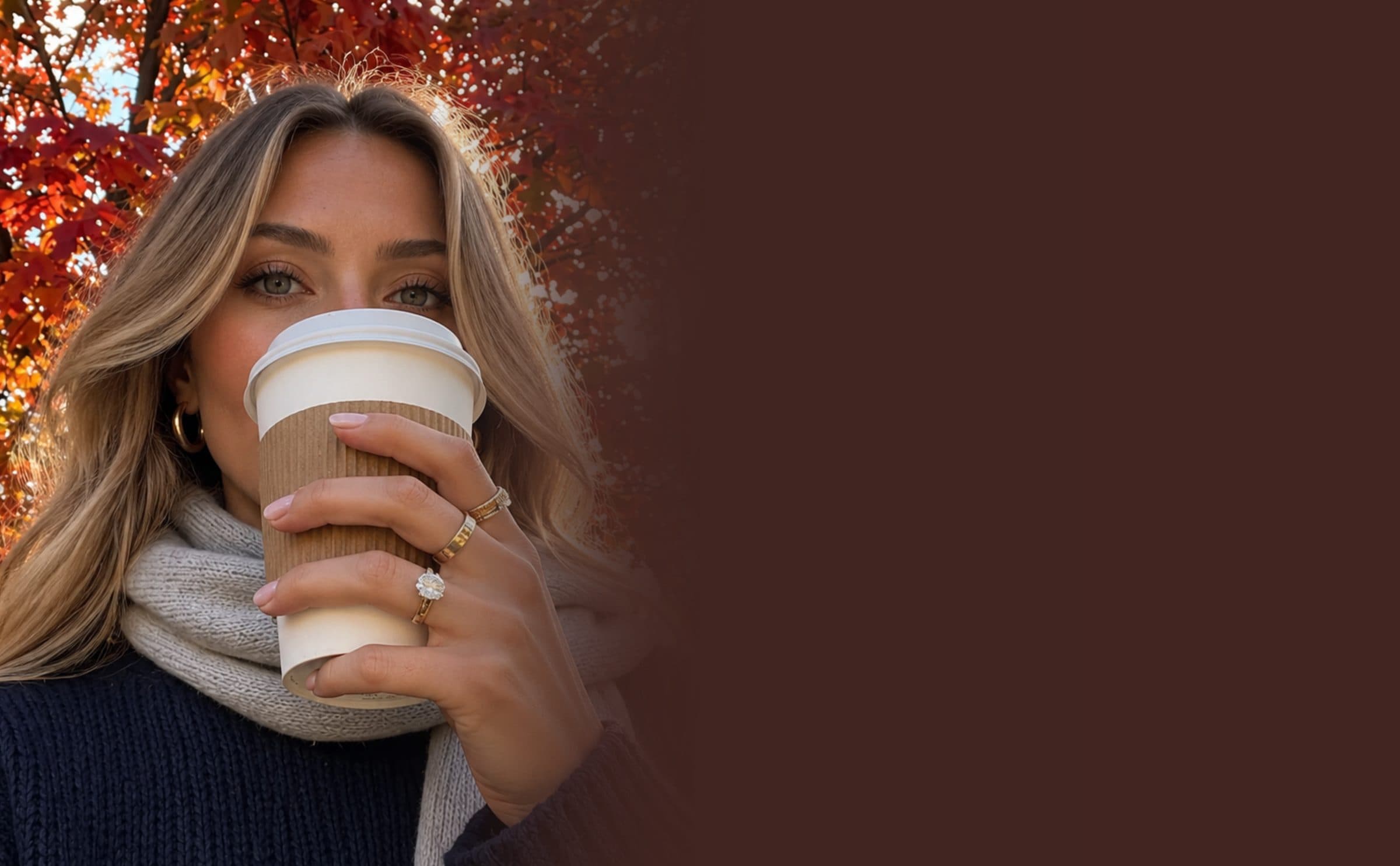 A woman drinking coffee under red autumn leaves