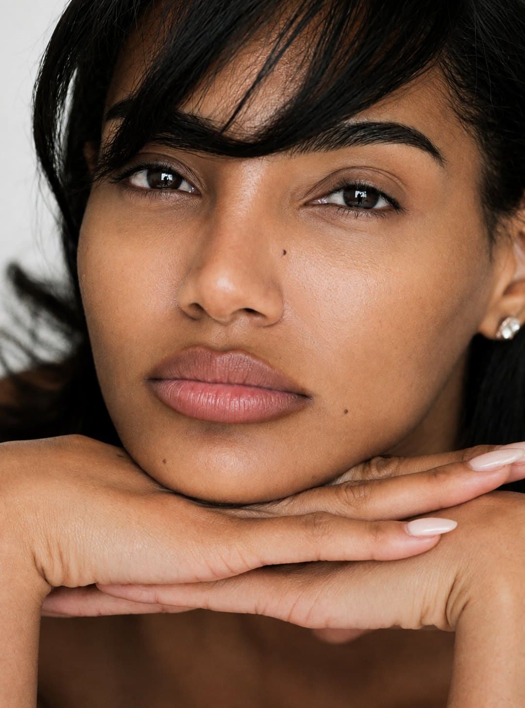 A woman with dark hair resting her chin on her crossed hands