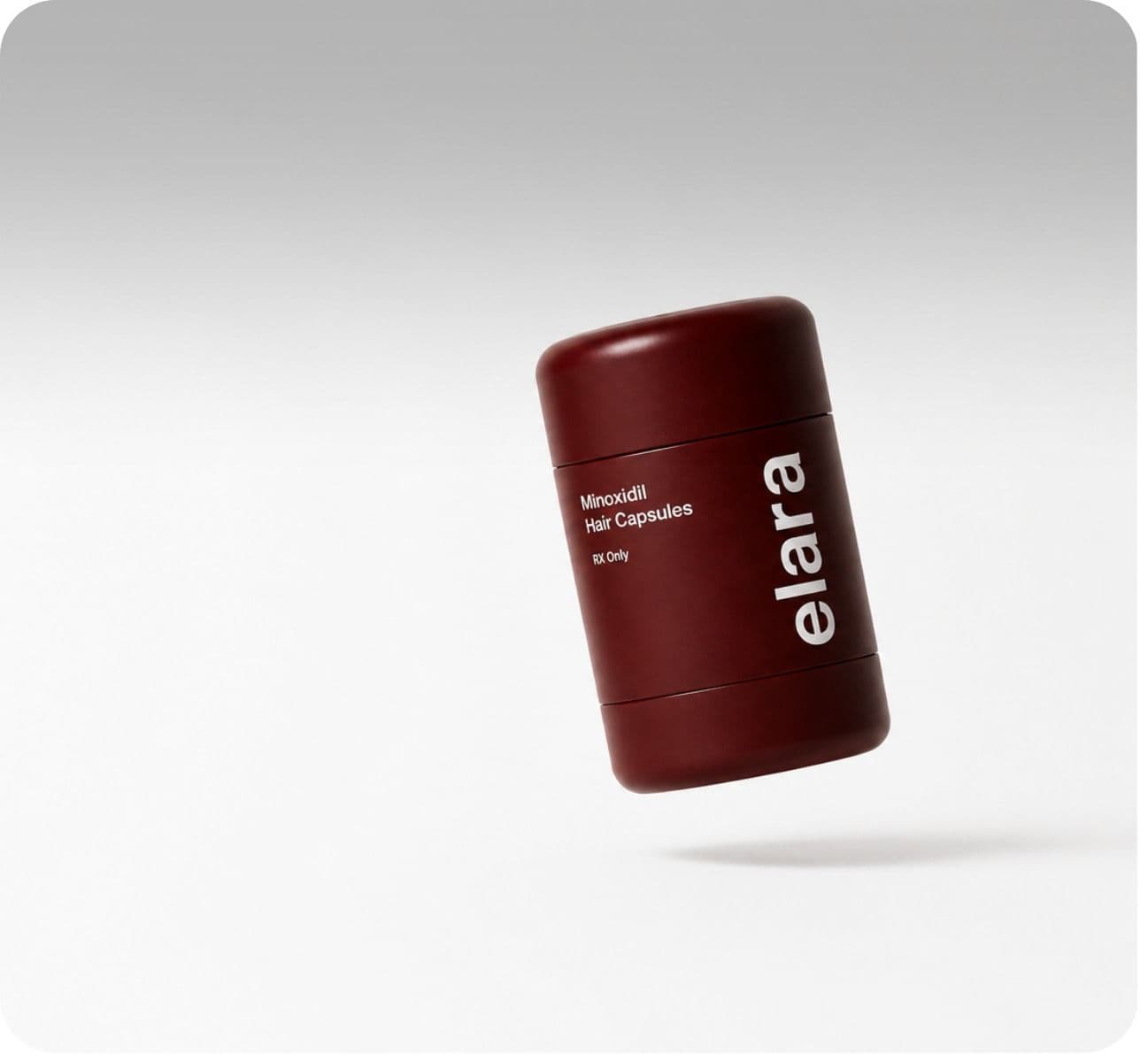 A maroon Elara minoxidil hair capsules bottle on a grey sweep