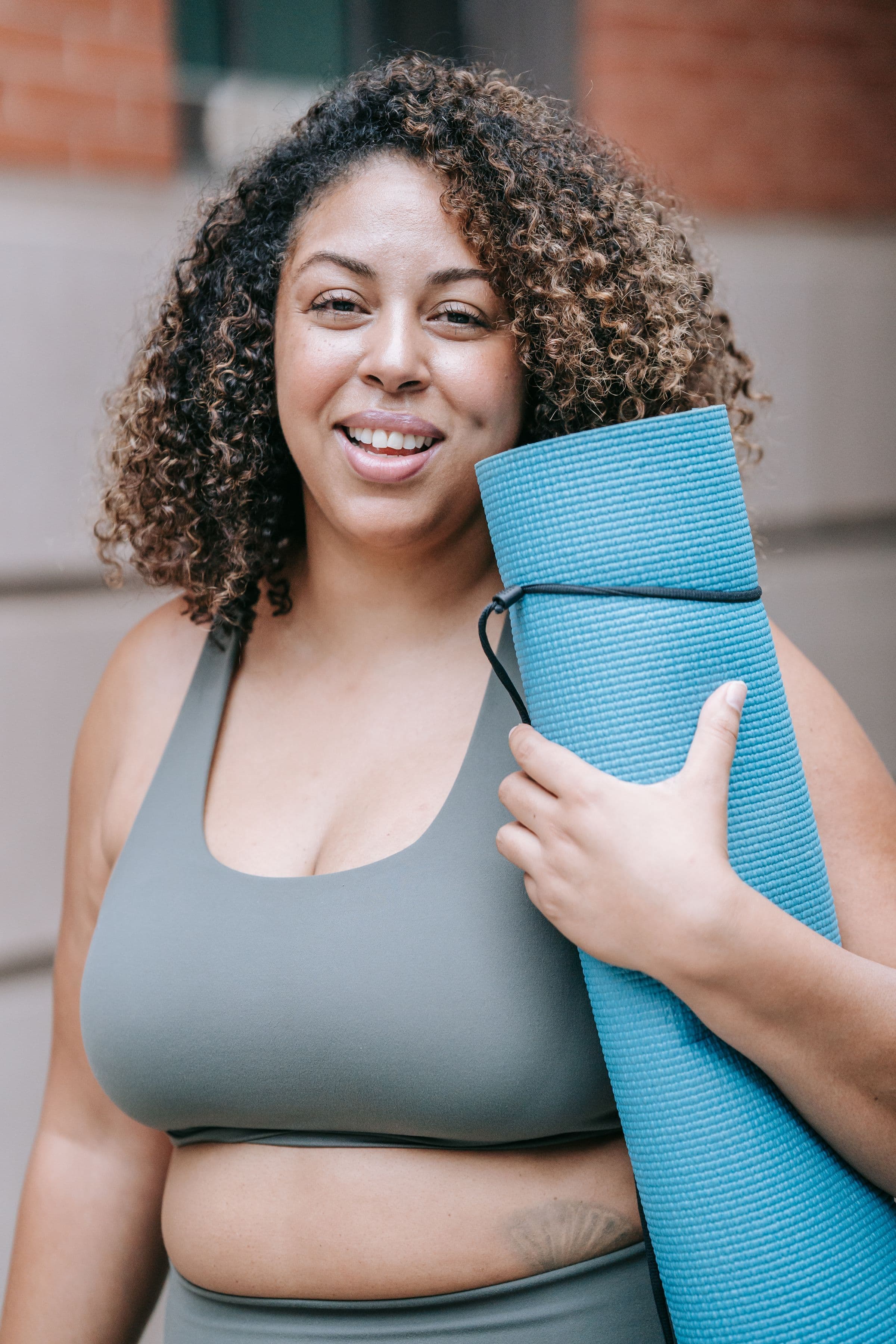 A smiling woman carrying a yoga mat, opening the question of whether to stack semaglutide with lipotropic injections