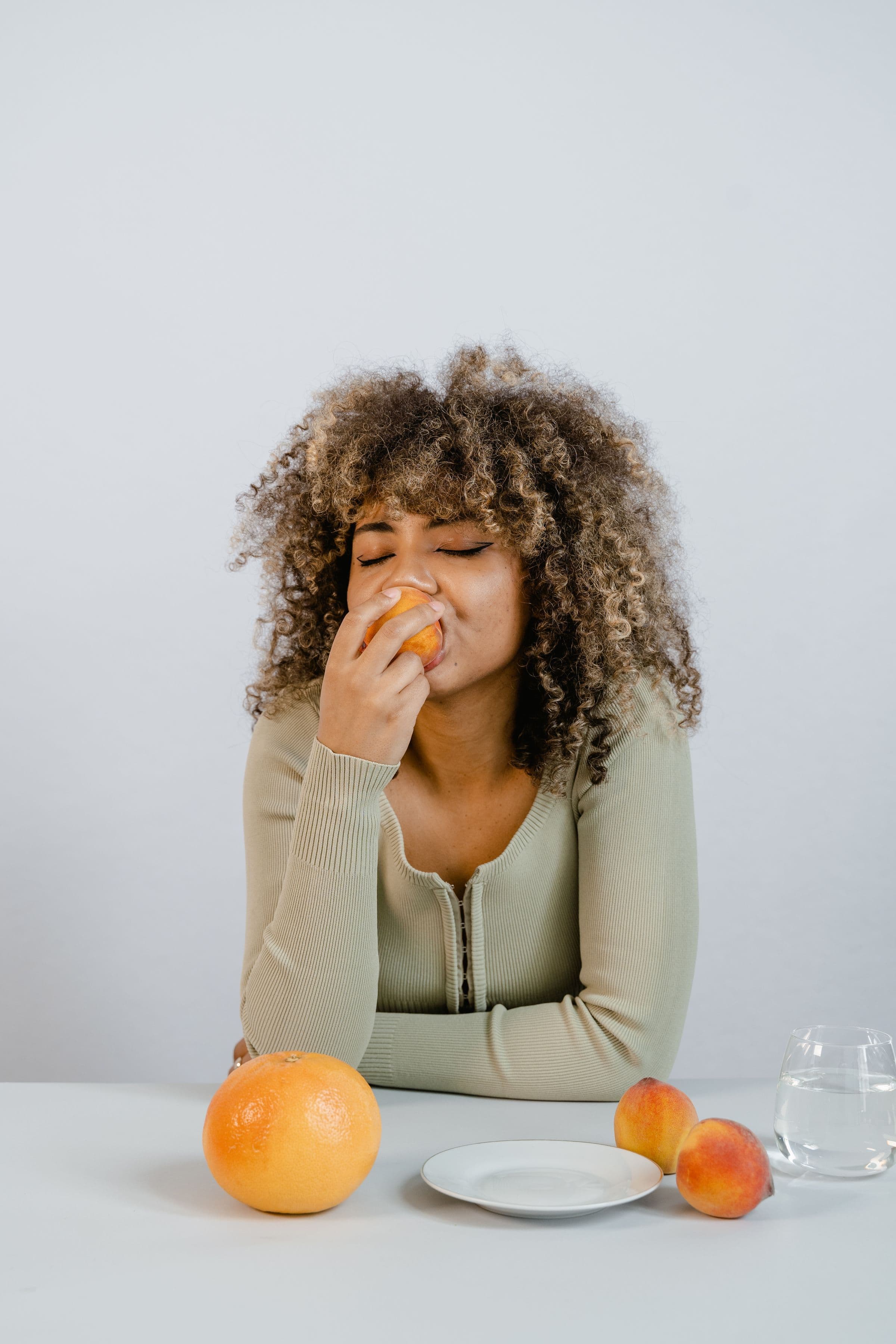 A woman at a table of citrus fruit, opening a guide to what to eat on semaglutide to avoid nausea and constipation