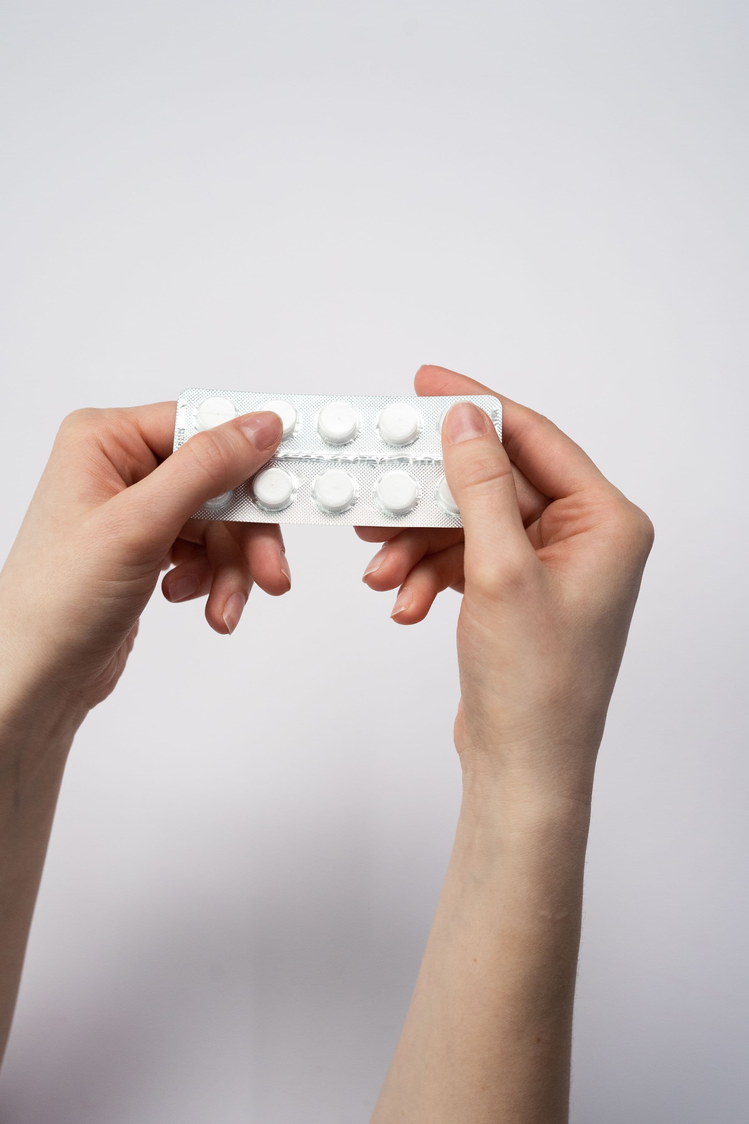 Two hands holding a blister pack of tablets, opening why tirzepatide affects birth control differently from semaglutide