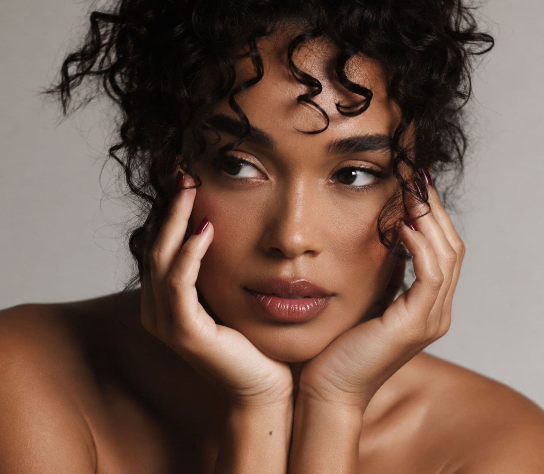A woman with curly hair resting her face on her hands