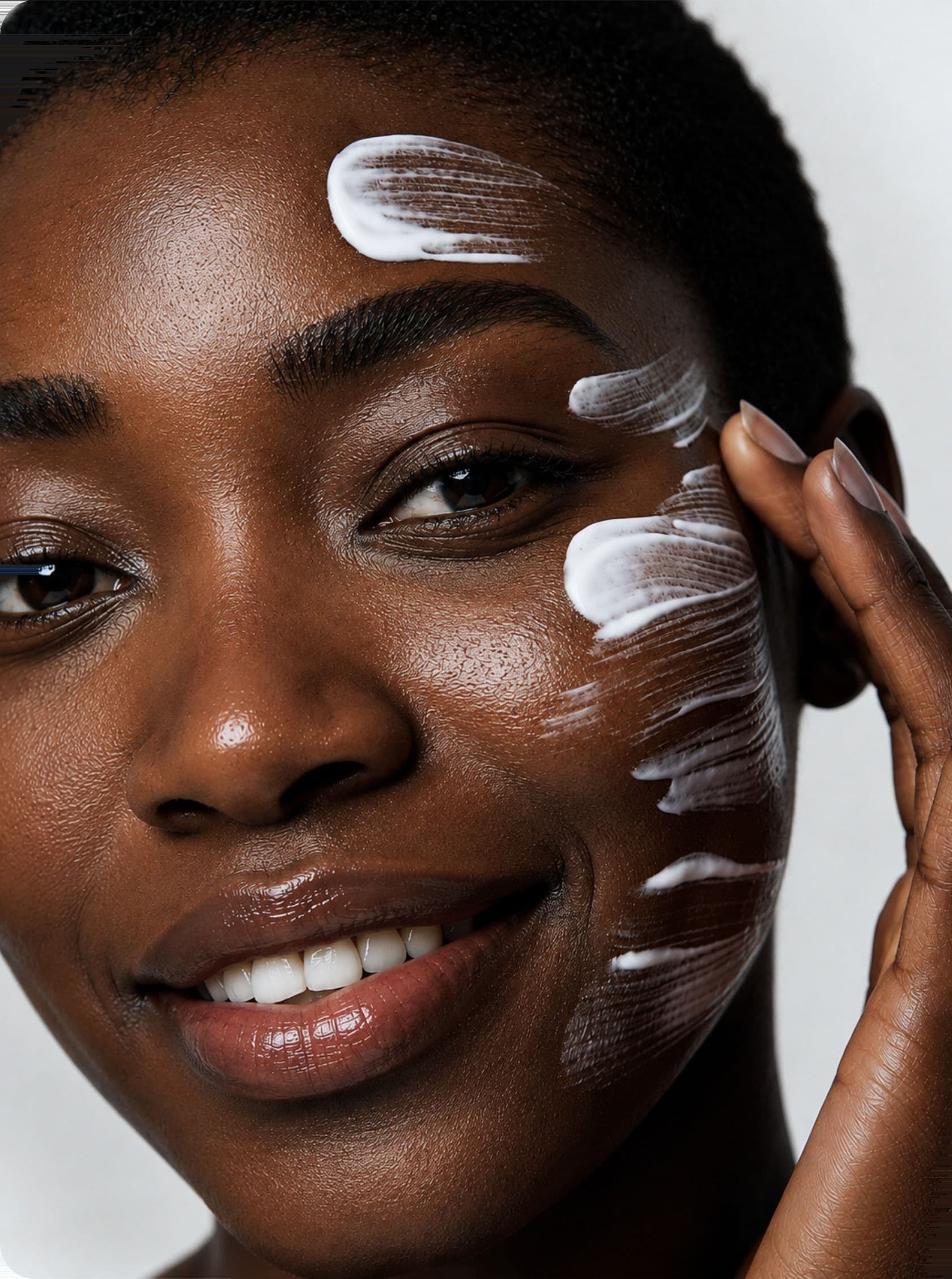 A woman smiling with cream on her cheek and forehead
