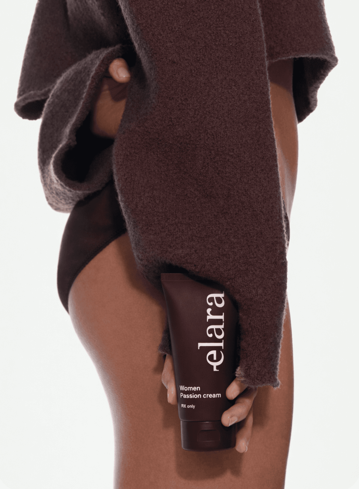A woman holding the elara passion cream under a wool wrap
