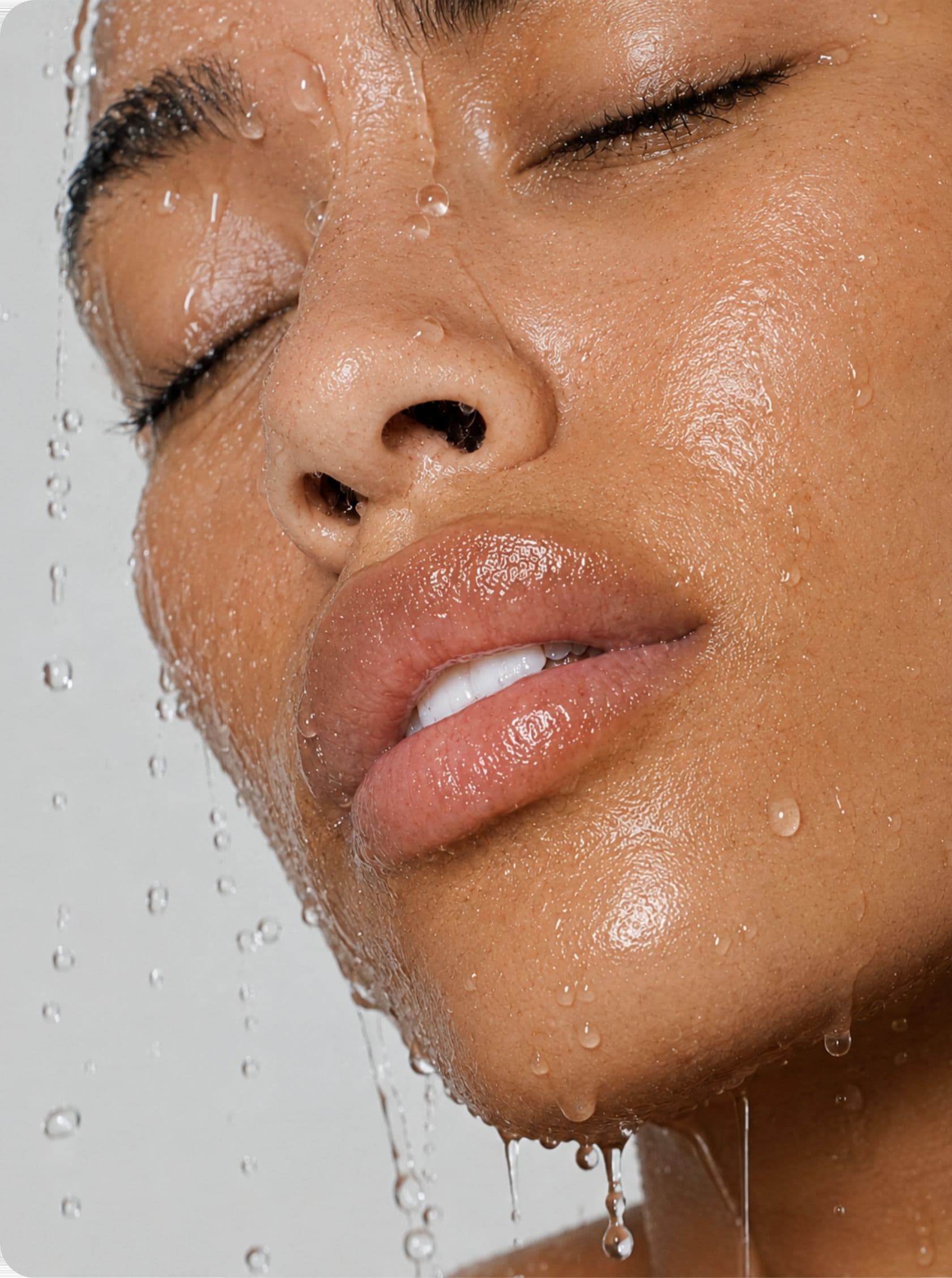 A woman under running water, eyes closed